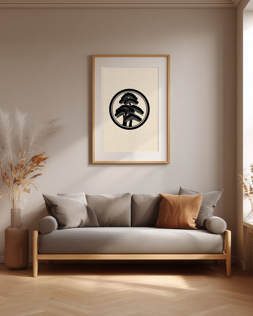 Matsu pine kamon print in black on cream, framed above a grey sofa in a japandi living room