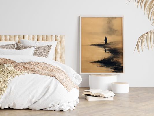 Sumi-e style ink print of a solitary figure on a misty shoreline with a reflection in the water, framed in light wood in a neutral bedroom above stacked books, Yugen Print