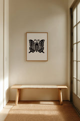 Agehachō butterfly kamon print in black on cream, framed above a low wooden bench in a minimalist entryway