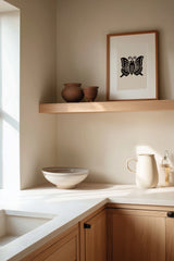 Agehachō butterfly kamon print in black on cream, framed on a wooden kitchen shelf with stoneware ceramics