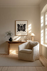 Agehachō butterfly kamon print in black on cream, framed above a wooden desk beside a cream armchair in a sunlit living room
