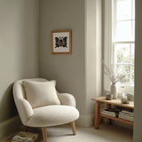 Agehachō butterfly kamon print in black on cream, framed above a cream reading chair by a sunlit window