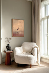 Crane at Dawn print framed beside a white armchair and side table in a reading corner by the window