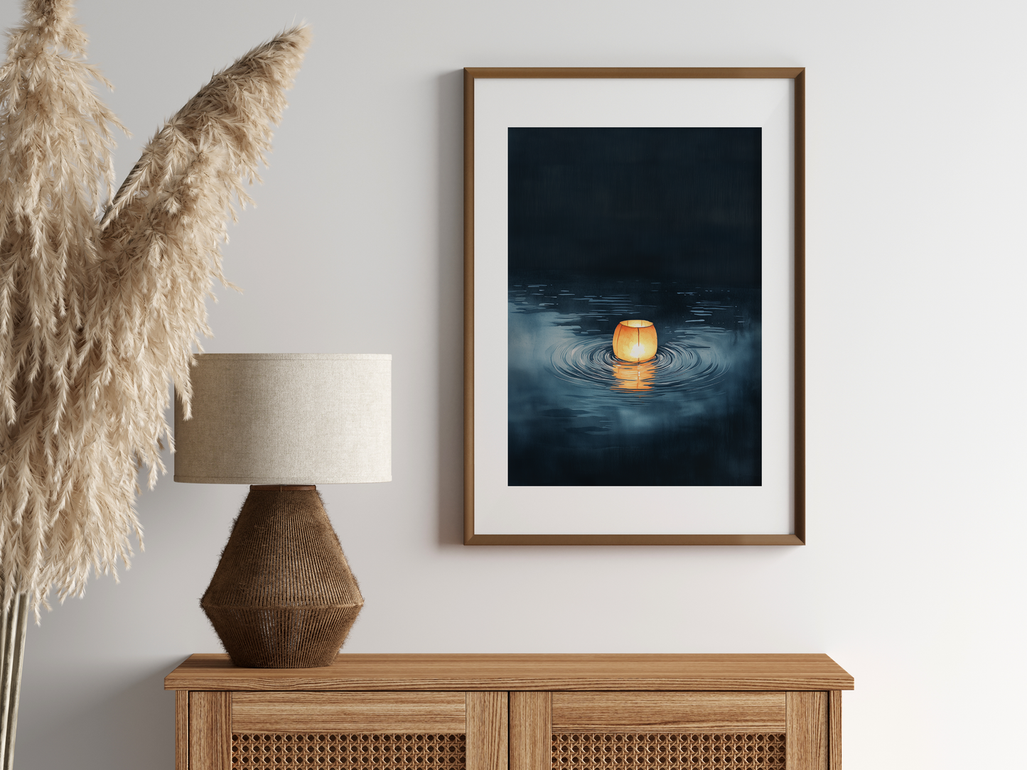 Sumi-e style indigo ink print of a single glowing paper lantern on dark water, oak frame above a rattan sideboard with a woven lamp and dried pampas grass, Yugen Print