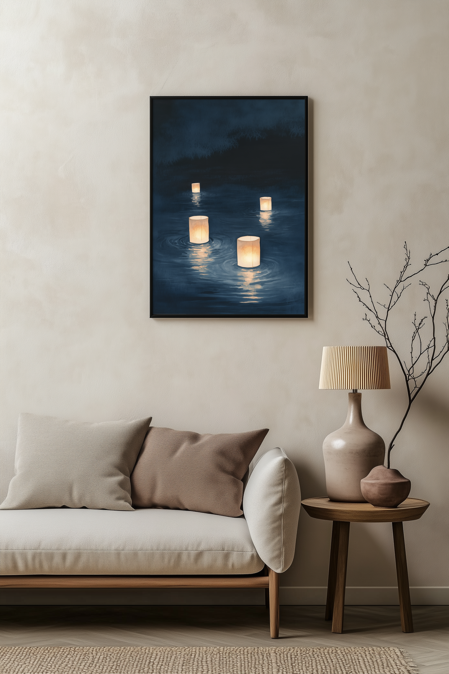 Sumi-e style indigo ink print of floating paper lanterns glowing on dark water, black frame above a pale linen sofa with a wooden side table and ceramic lamp, Yugen Print
