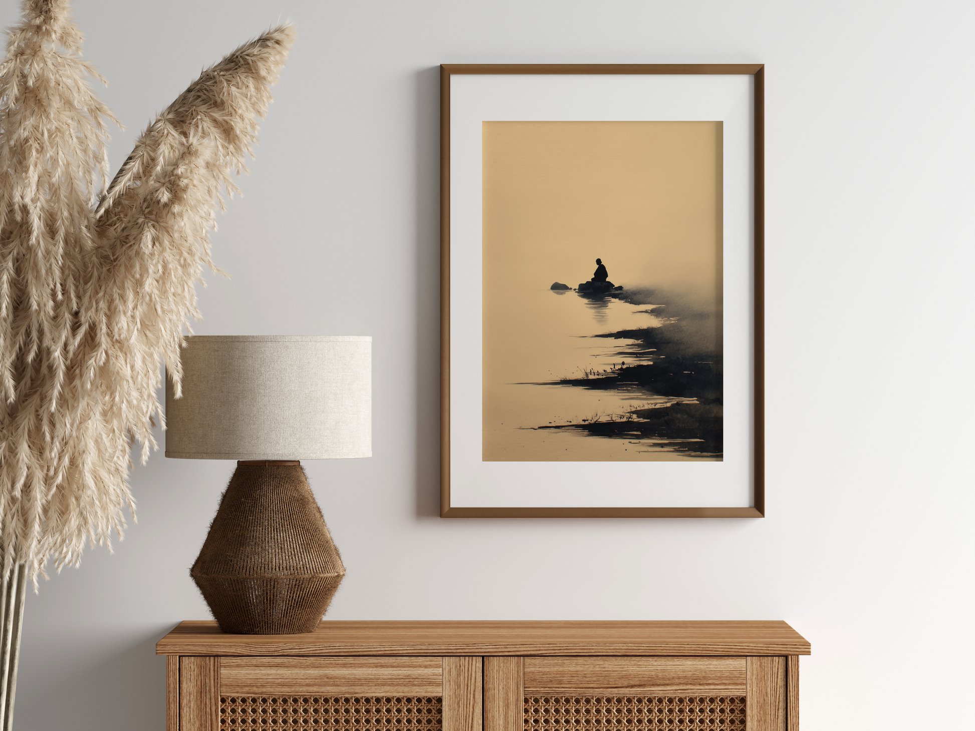 Sumi-e style ink print of a small figure on a rock surrounded by still water, in an oak frame above a cane sideboard with a rattan lamp and pampas, Yugen Print