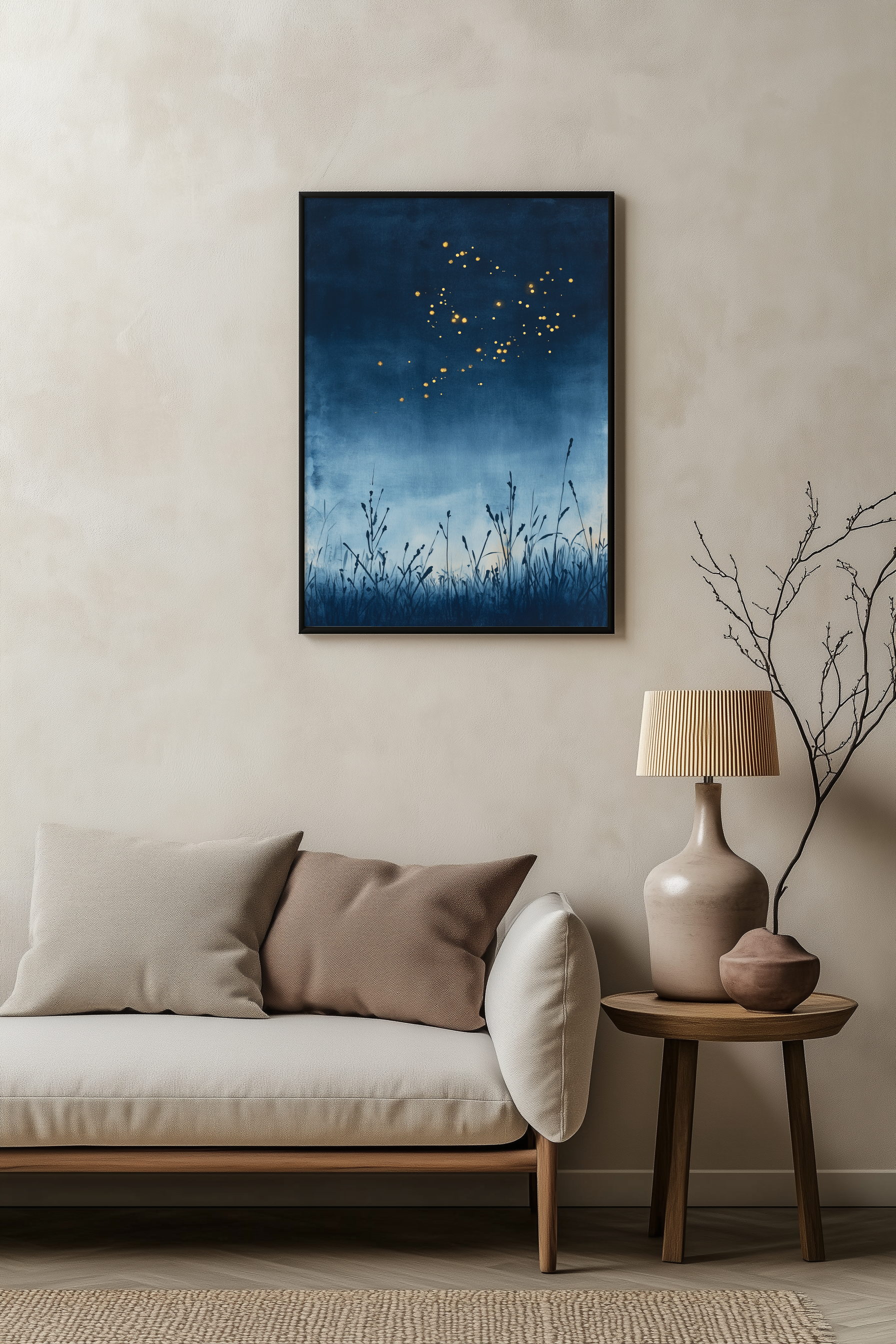 Sumi-e style indigo ink print of fireflies over a summer night, black frame above a pale linen sofa with a wooden side table and ceramic lamp, Yugen Print