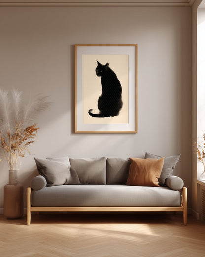 A framed art print featuring a black cat silhouette on a cream background, hanging on a beige wall above a modern gray sofa in a styled living room.