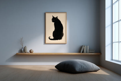 A framed art print of a black cat silhouette on a beige background, hanging on a light blue-gray wall in a minimalist room with a wooden floating shelf, books, and a floor cushion.