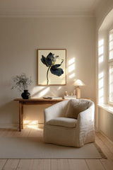Kintsugi Lotus print shown framed in a Scandi living room (4:5 version), a dark ink lotus flower with gold-edged petals on a curved stem above rippling water