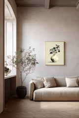 Kintsugi Moon Jar print shown framed in a living room with plaster walls, a round white moon jar with gold kintsugi seams holding a spray of dark leaves on a pale ground