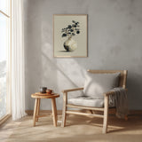 Kintsugi Moon Jar print shown framed in a reading corner, a round white moon jar with gold kintsugi seams holding a spray of dark leaves on a pale ground
