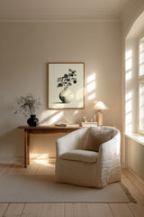 Kintsugi Moon Jar print shown framed in a Scandi living room, a round white moon jar with gold kintsugi seams holding a spray of dark leaves on a pale ground