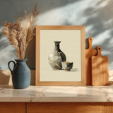 Kintsugi Sake Set print shown framed in a kitchen, a grey sake flask and small cup mended with gold kintsugi seams on a cream ground