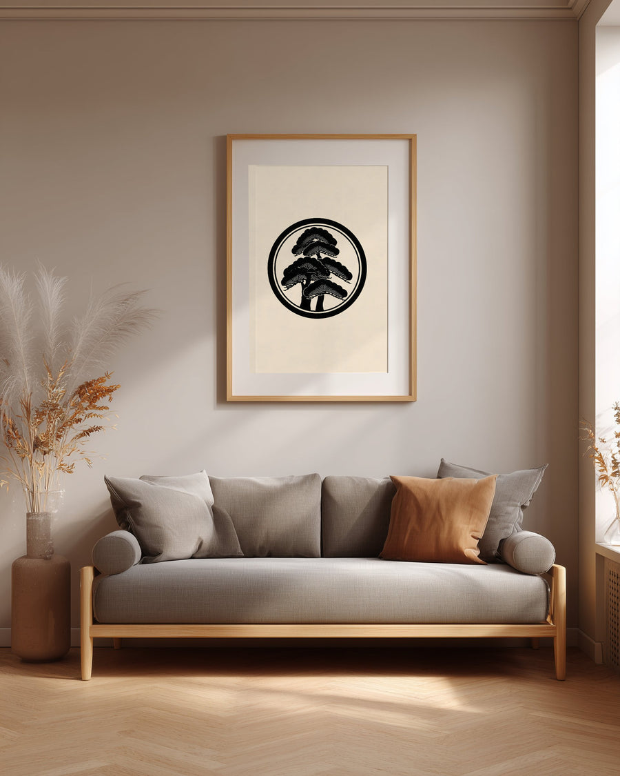 Matsu pine kamon print in black on cream, framed above a grey sofa in a japandi living room