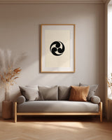 Mitsudomoe swirl kamon print in black on cream, framed above a grey sofa in a japandi living room