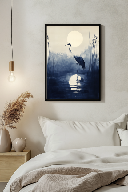 Sumi-e style indigo ink print of a crane silhouetted beneath a full moon, black frame above white bedding beside a warm pendant light in a serene evening bedroom, Yugen Print