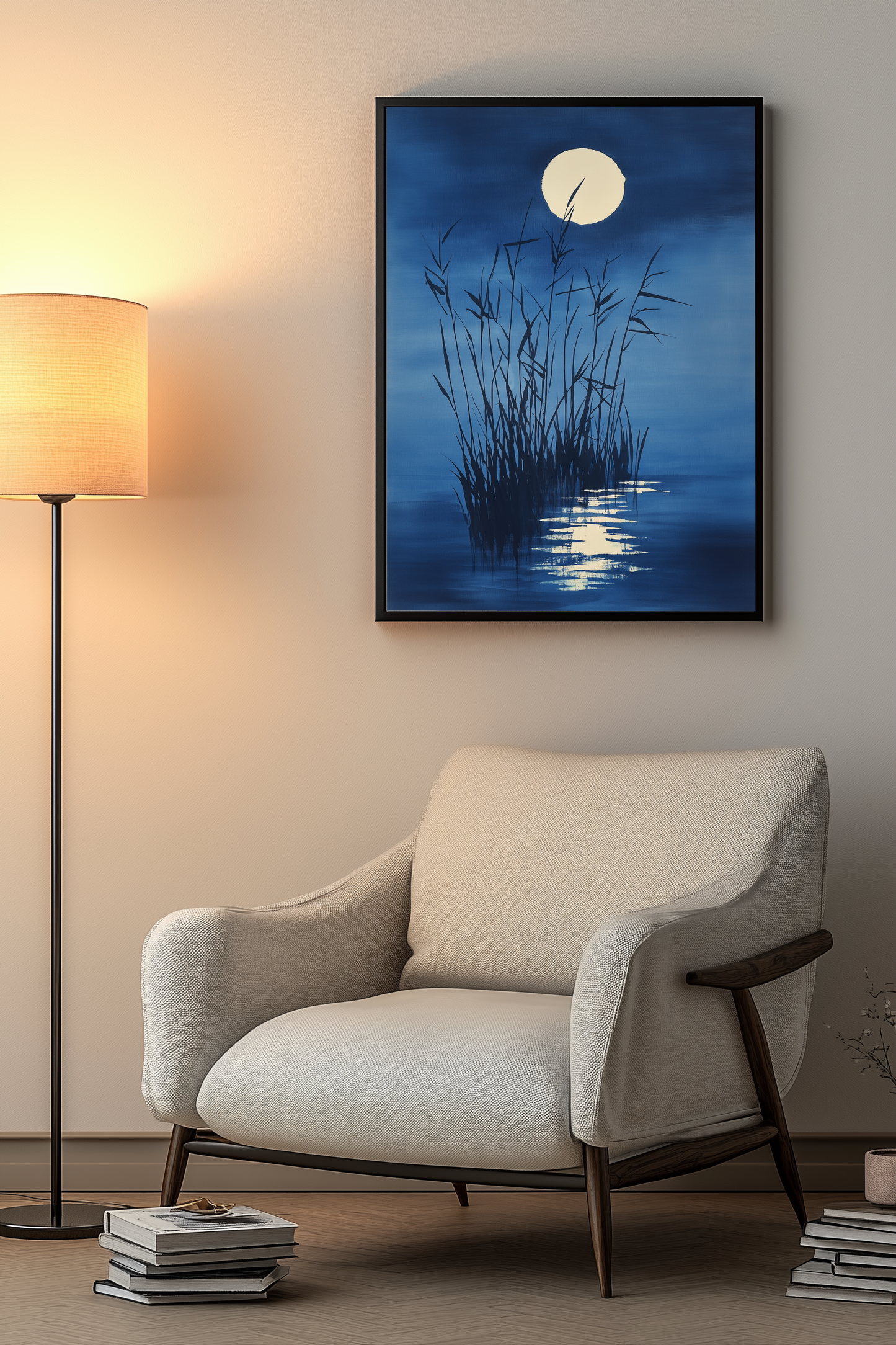 Sumi-e style indigo ink print of tall reeds against a full moon on still water, black frame above a cream armchair beside a warm floor lamp in a cosy reading nook, Yugen Print