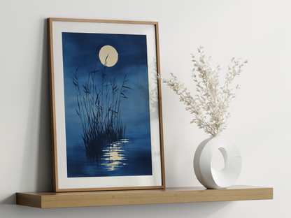 Sumi-e style indigo ink print of tall reeds beneath a full moon, oak frame leaning on a floating wood shelf beside a white ceramic vase, Yugen Print