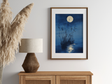 Sumi-e style indigo ink print of moonlit reeds and a full moon reflection, oak frame above a rattan sideboard with a woven lamp and dried pampas grass, Yugen Print