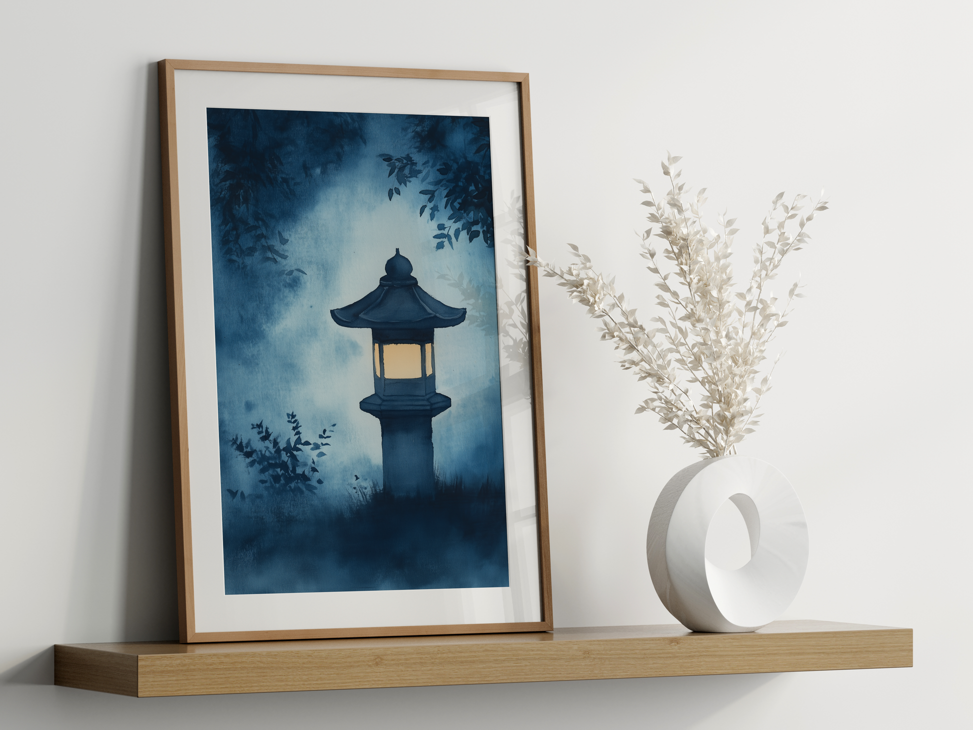 Sumi-e style indigo ink print of a glowing stone lantern in a misty garden, oak frame leaning on a floating wood shelf beside a white ceramic vase, Yugen Print