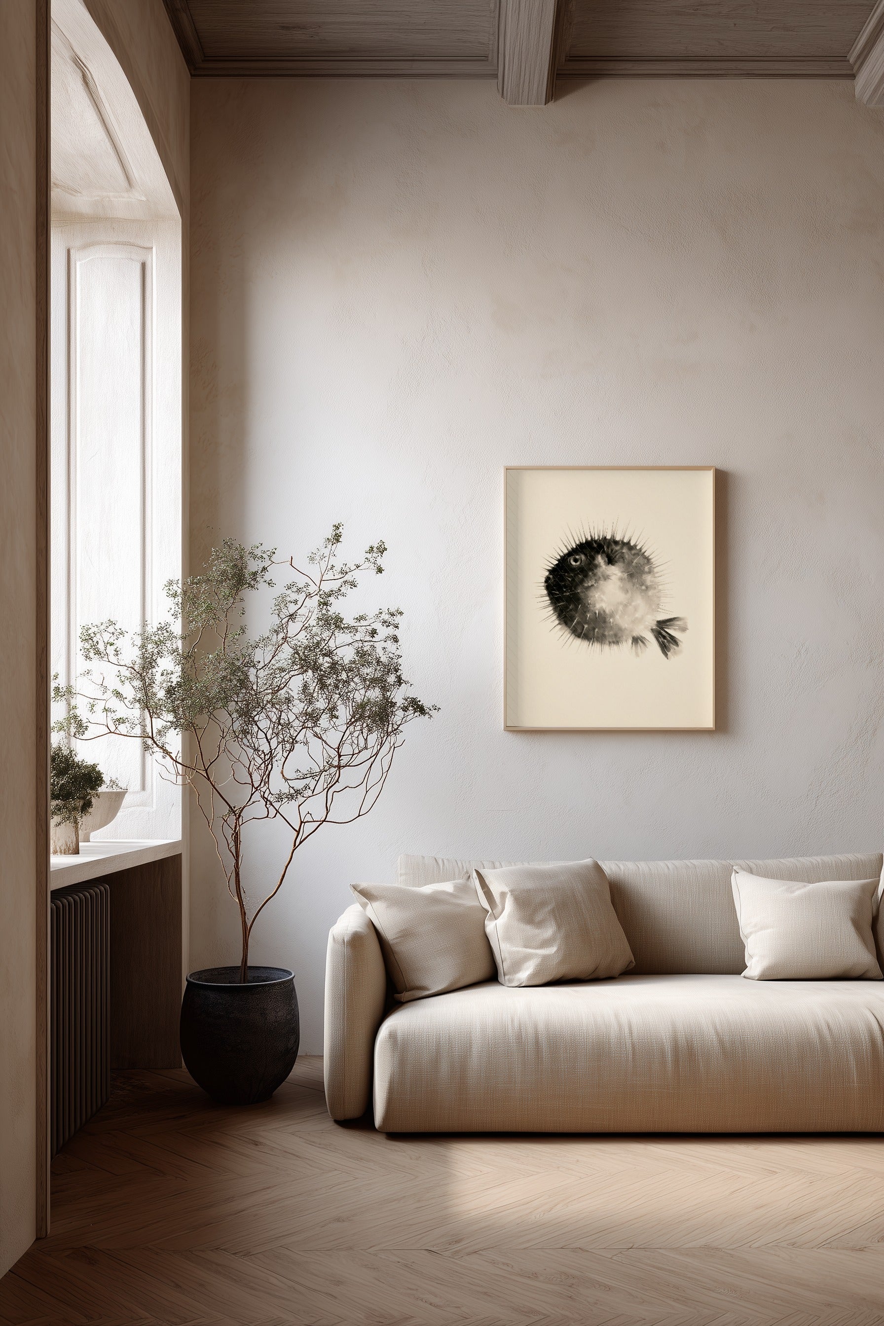 A minimalist living room scene featuring a cream-colored sofa with matching pillows, a large potted dried plant, and a framed black and white fugu art print on the wall.