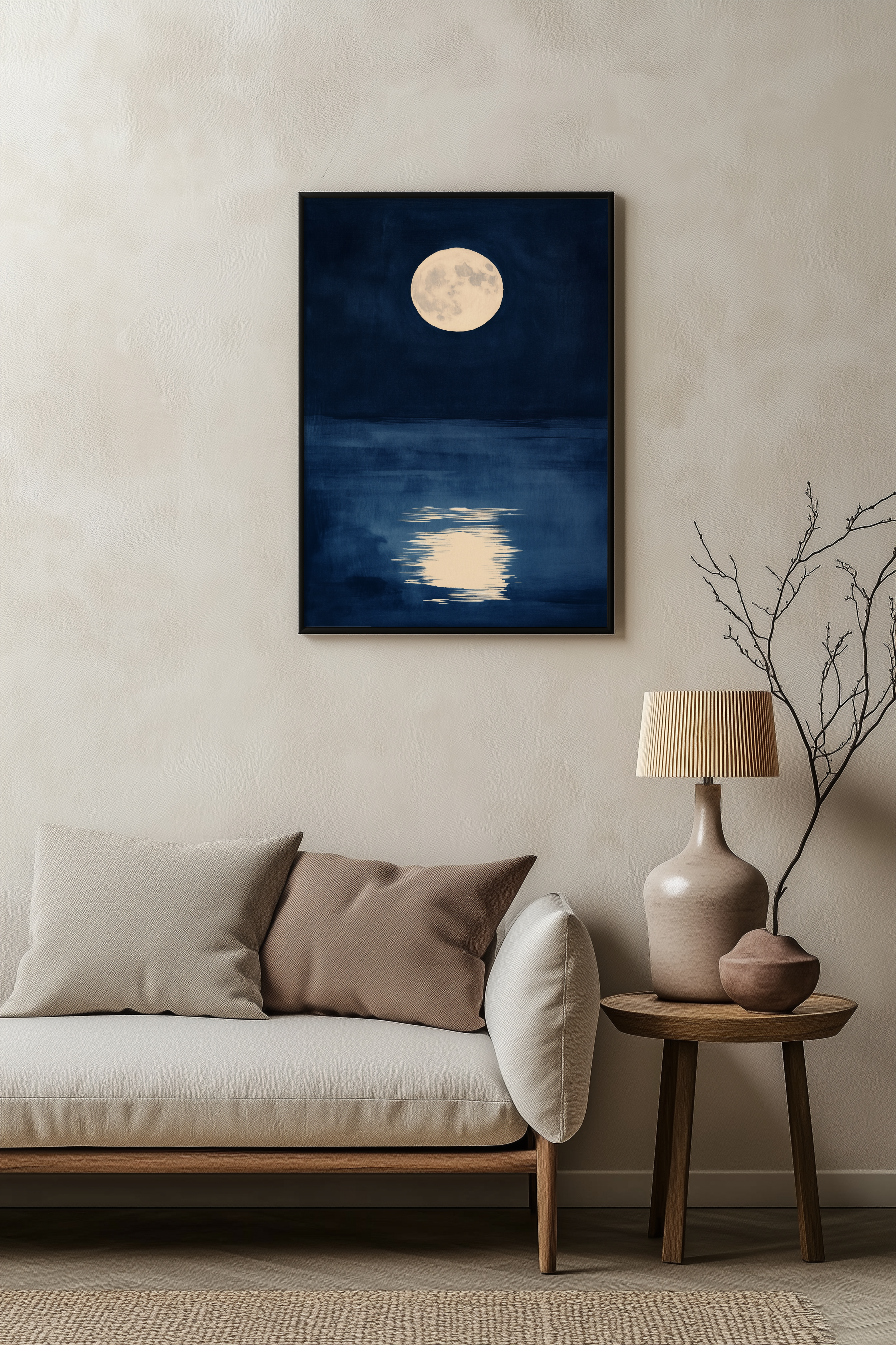 Sumi-e style indigo ink print of a full moon over dark water, black frame above a pale linen sofa with a wooden side table and ceramic lamp, Yugen Print