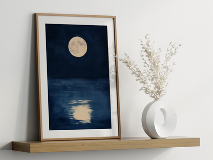 Sumi-e style indigo ink print of a full moon reflected on dark water, oak frame leaning on a floating wood shelf beside a white ceramic vase, Yugen Print