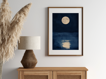 Sumi-e style indigo ink print of a full moon over still water, oak frame above a rattan sideboard with a woven lamp and dried pampas grass, Yugen Print