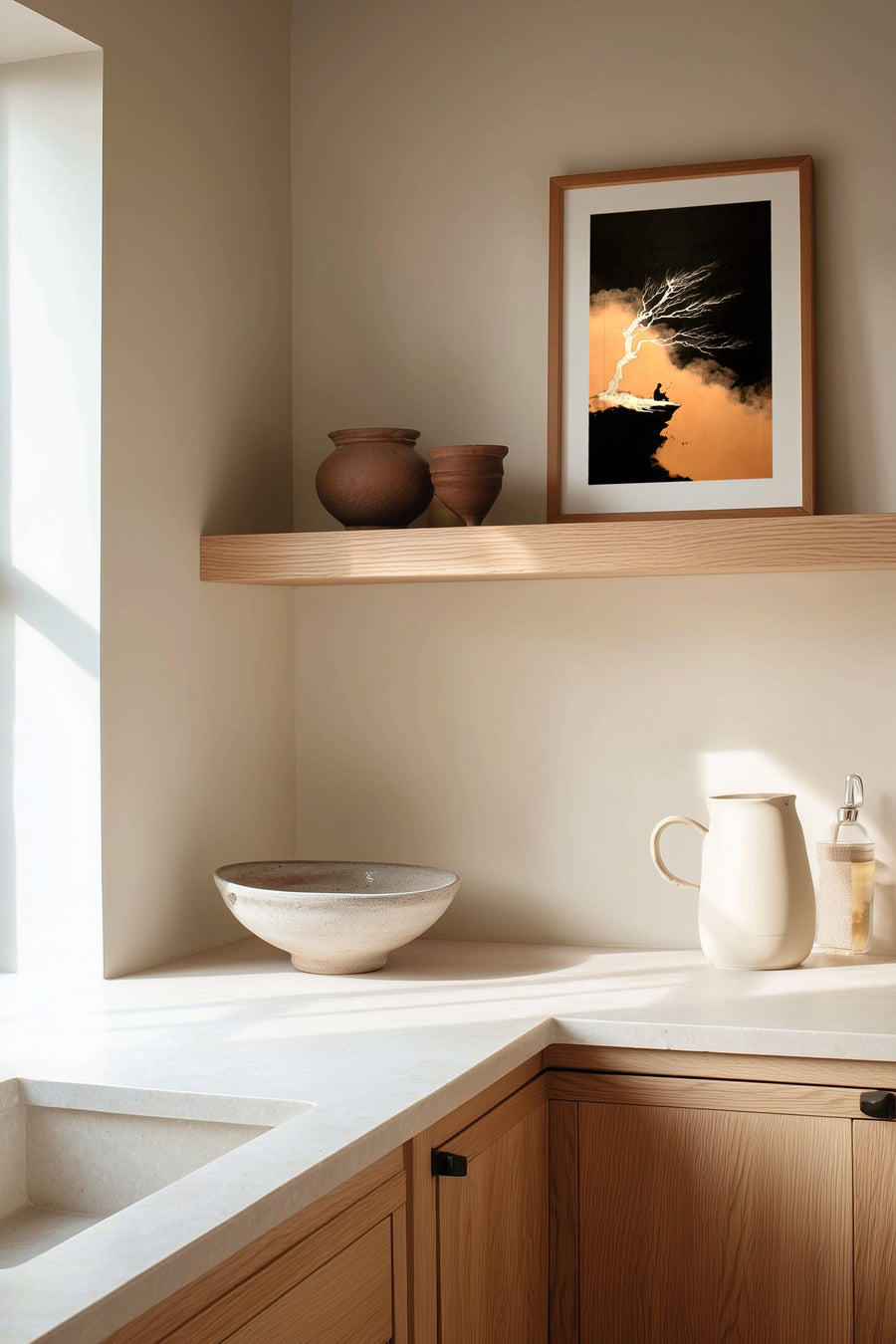 The Cliff Tree sumi-e print framed on the wall above a wood shelf in a warm ivory kitchen corner