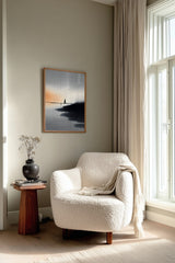 The Narrow Crossing sumi-e print framed beside a white armchair and side table in a reading corner by the window