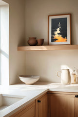 The Pale Wanderer sumi-e print framed on the wall above a wood shelf in a warm ivory kitchen corner