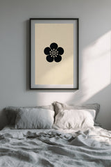 Ume plum blossom kamon print in black on cream, framed above the bed in a calm bedroom with grey linen bedding