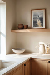 Wayfarer's Reflection sumi-e print framed on the wall above a wood shelf in a warm ivory kitchen corner