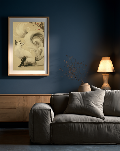 Sumi-e style ink print of a white nine-tailed fox seated with its gaze lifted toward a plum blossom branch, tails flowing into mist, black ink on cream paper, framed in oak on a deep blue living room wall above a grey sofa with a table lamp, Yugen Print