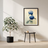 Two Hydrangeas print in a black frame beside a potted tree and a small side table, Yugen Print