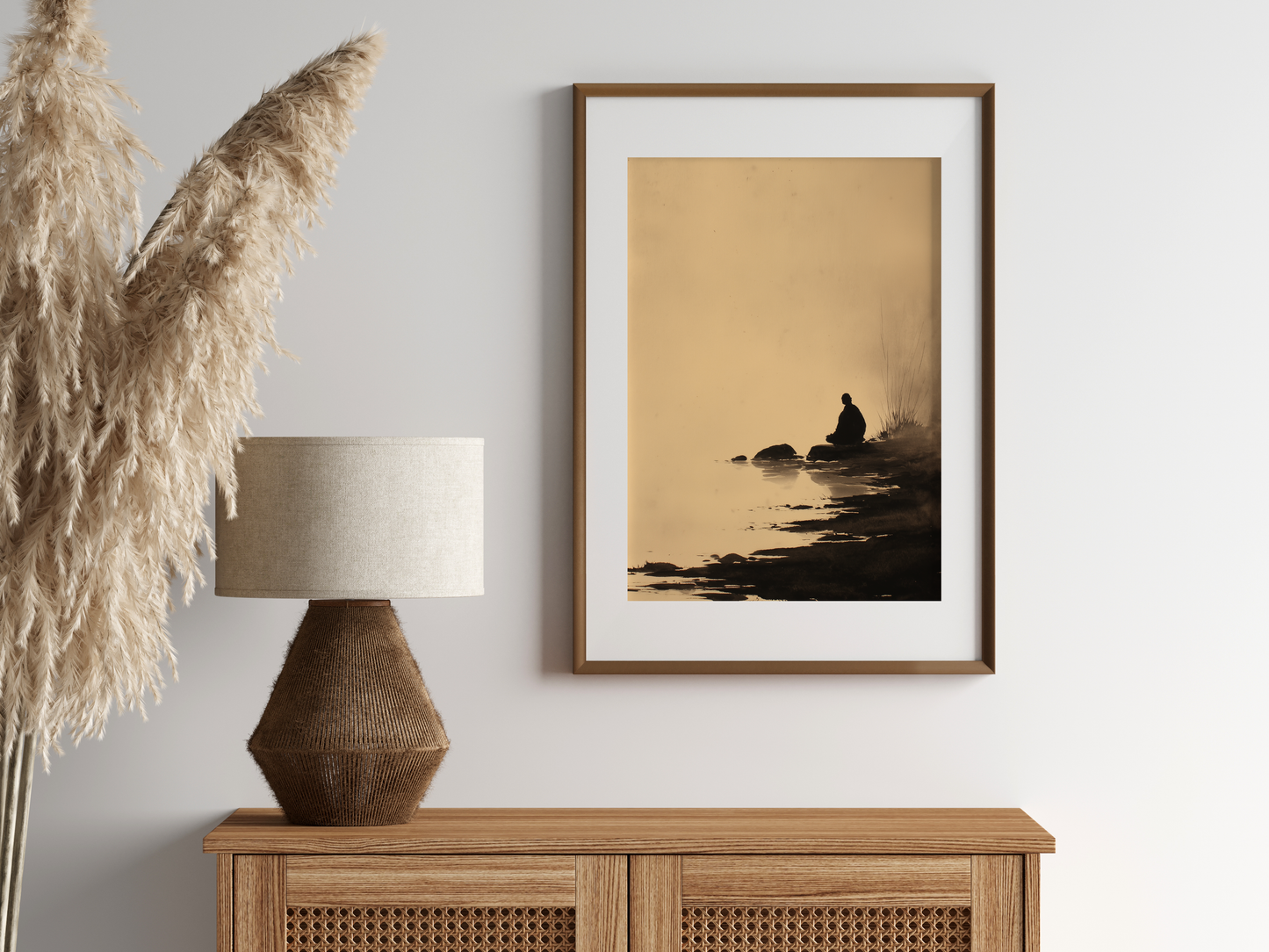 Sumi-e style ink wash print of a small figure seated beside still water, in an oak frame above a cane sideboard with a rattan lamp and pampas, Yugen Print